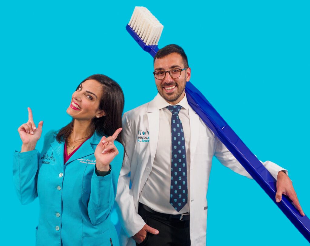 Dr. Jacquie and Dr. K. joyfully dance with giant toothbrush prop